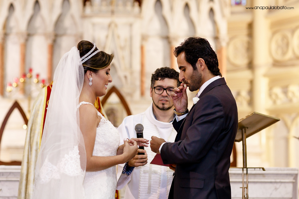 Noivo beija aliança da noiva no altar