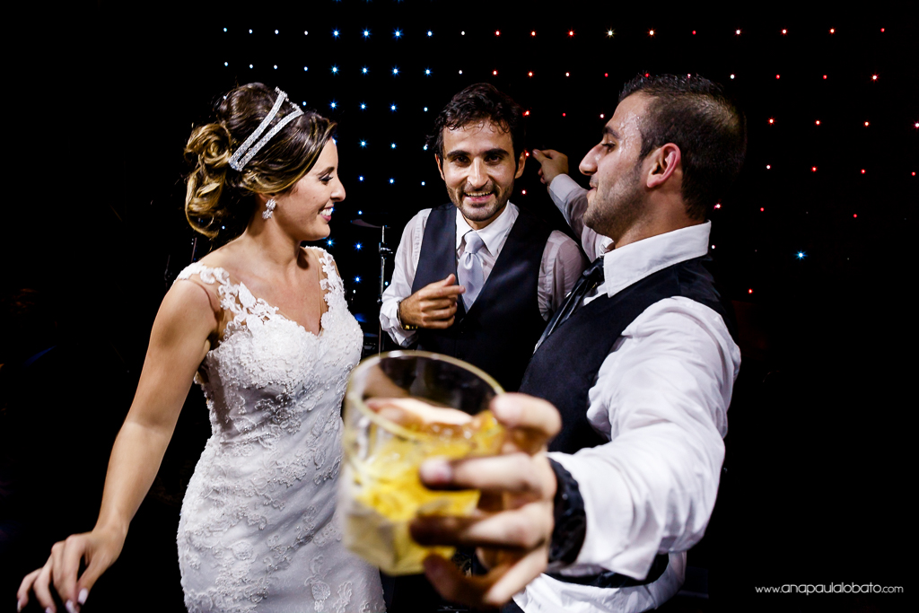 Noivos dançam com padrinho no palco de casamento