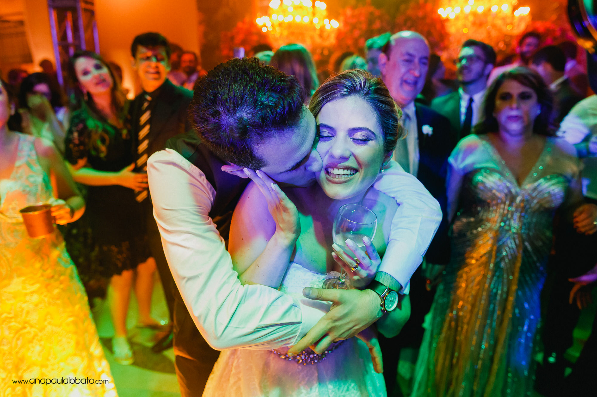 Groom hugs and kisses the bride in a colorful moment